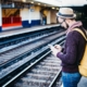 Man waiting on train platform with phone