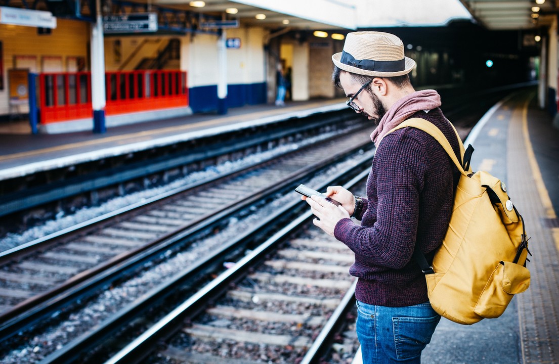 Man waiting on train platform with phone